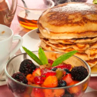 Desayuno americano: omelette con jamón y queso, bacon y pancakes